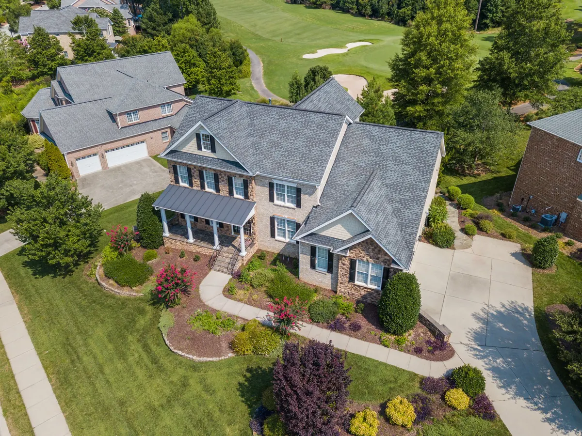 Aerial view of a suburban home with a curved driveway, shaped planting beds and a landscaped lawn