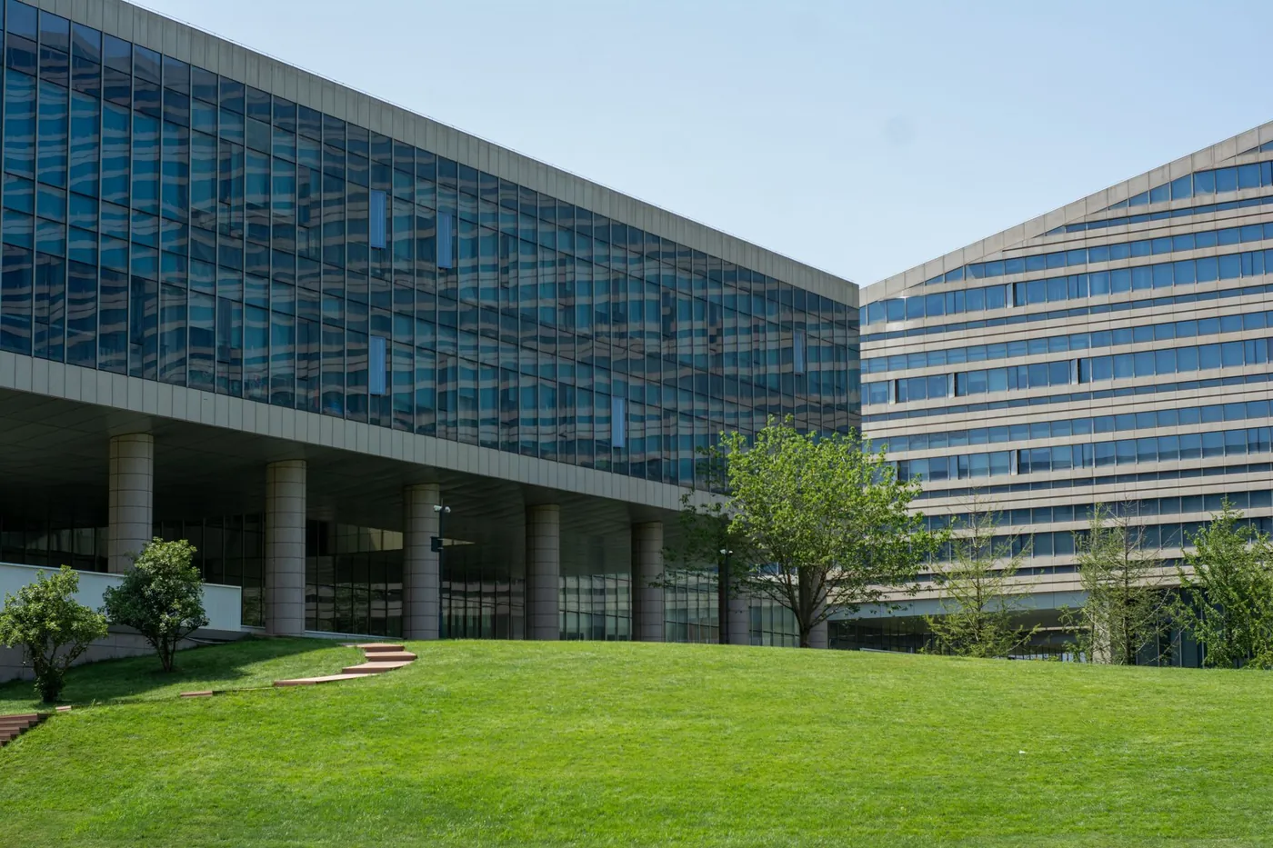 Glass-fronted office building fronted by a wide, closely maintained commercial lawn